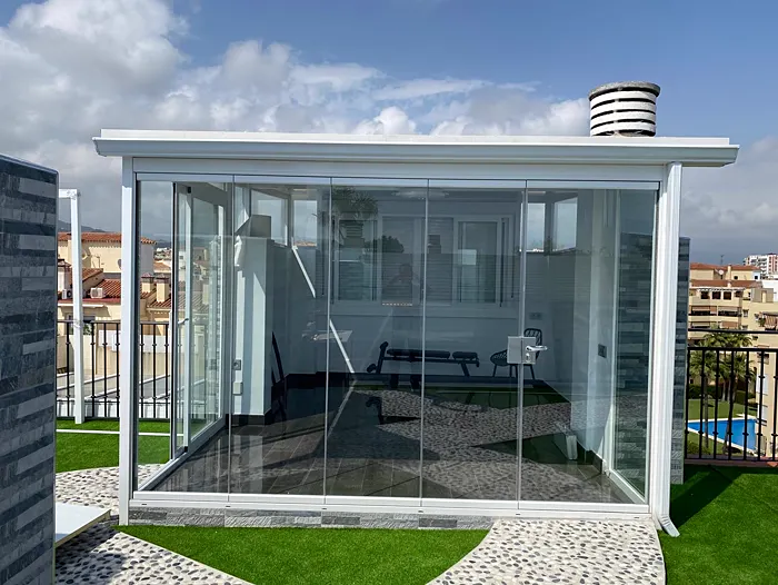 Cerramiento de cristal en la terraza de un ático con césped
