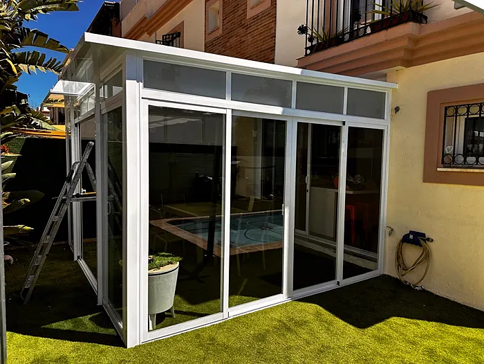 Cerramiento de terraza con perfilería blanca junto a la piscina