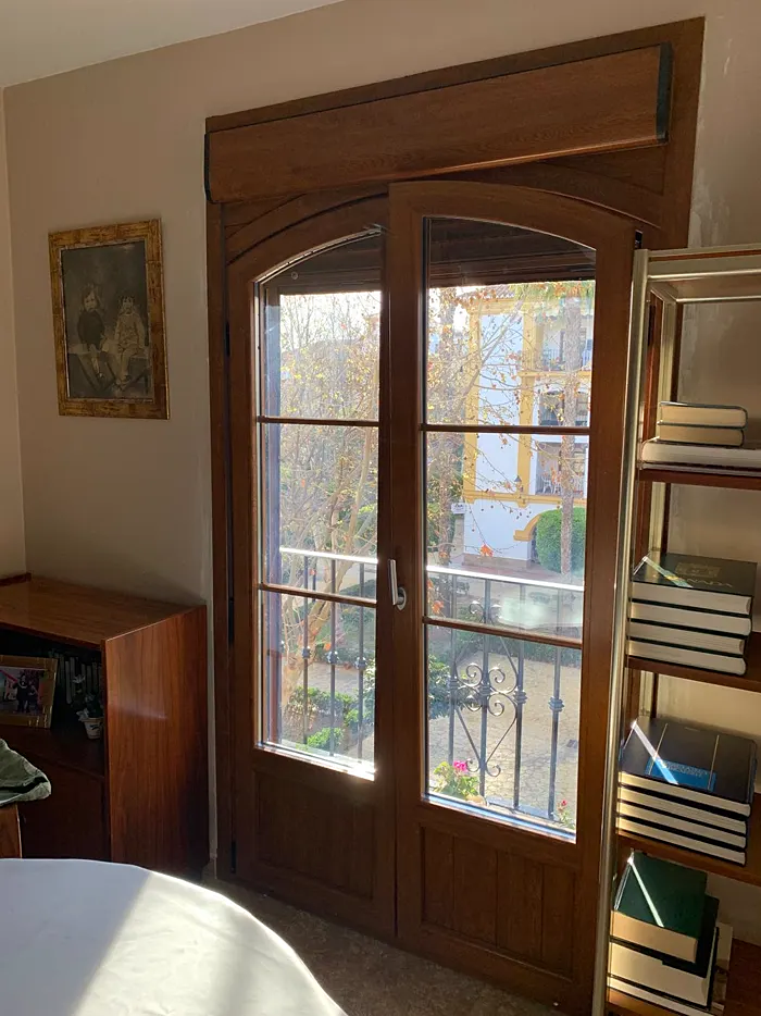 Puerta balconera de dos hojas en arco, acabado imitación madera