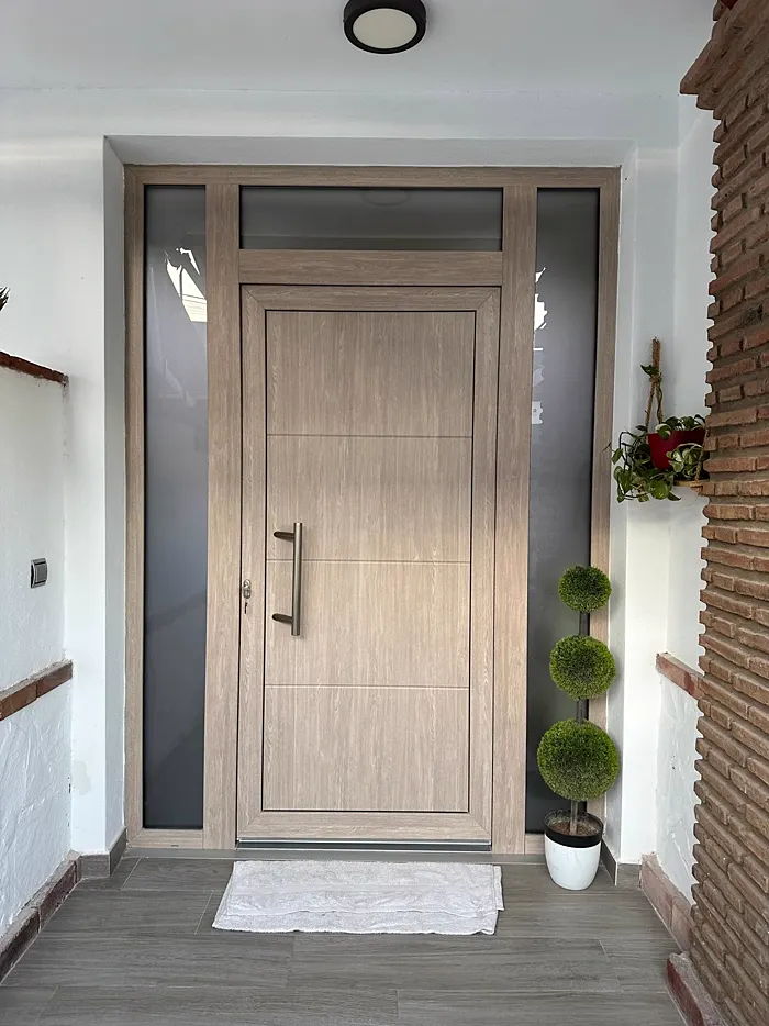 Puerta de entrada en acabado imitación madera con fijos laterales de vidrio