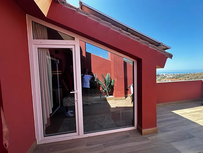 Puerta y fijos acristalados en la terraza de un ático con vistas al mar