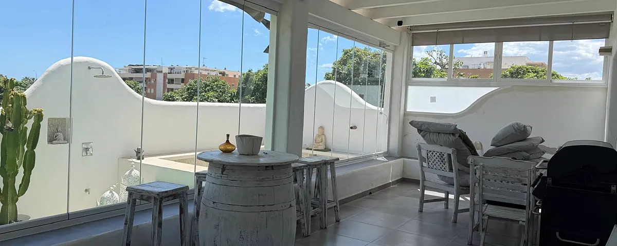 Terraza cubierta cerrada con cortinas de cristal, con la vista despejada hacia fuera